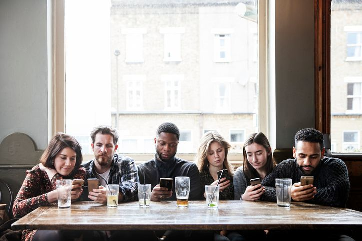 6 friends at a pub with phones 