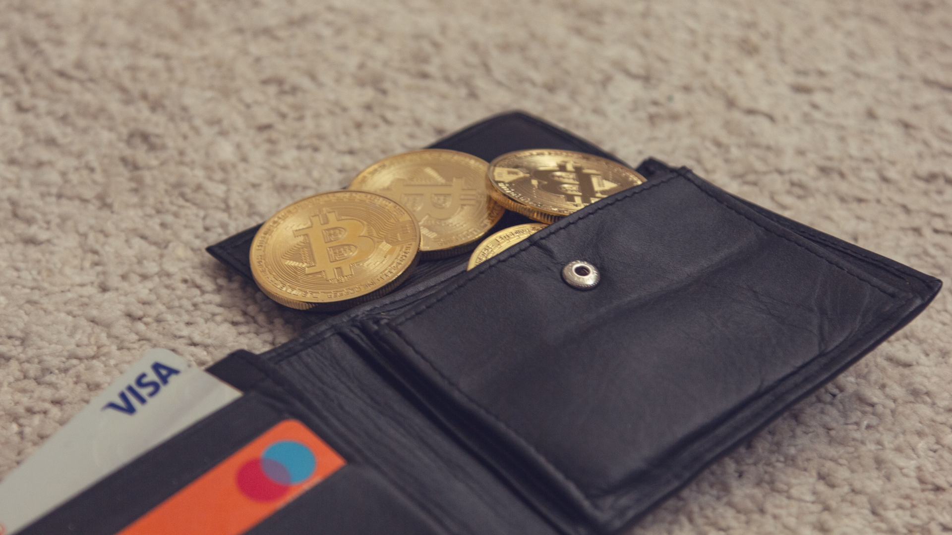 A black wallet with Bitcoin coins