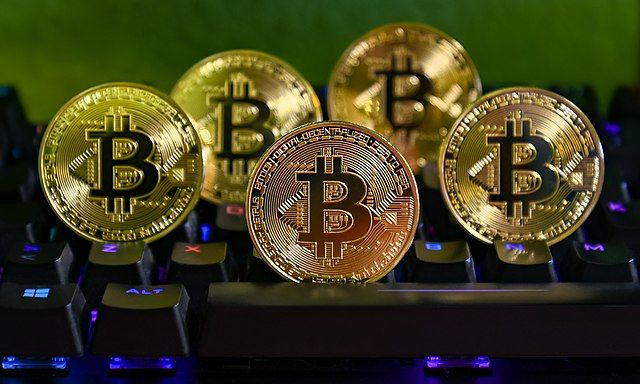 Five Bitcoin coins on a keyboard. 