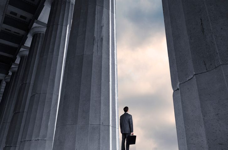 Man Standing Next To Columns Looks Into Distance - stock photo