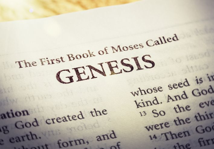 A Holy Bible is open to the first page of the first book of the Old Testament, Genesis.