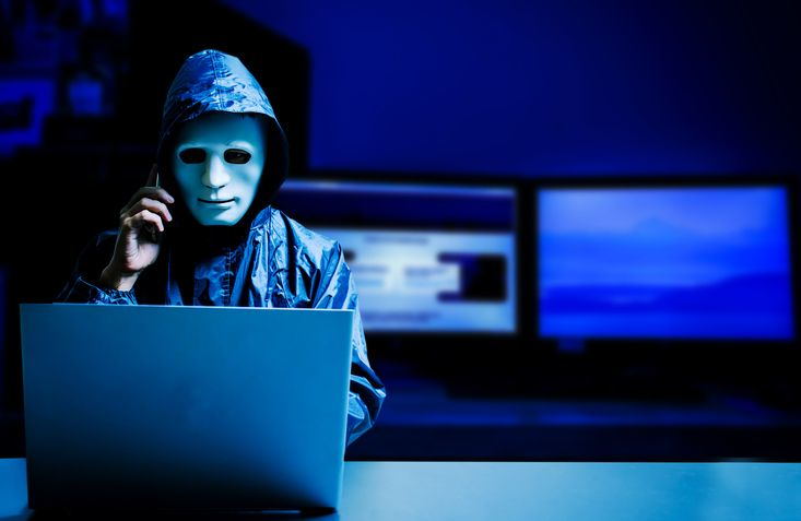 A stock image of a masked hacker in front of the laptop. 