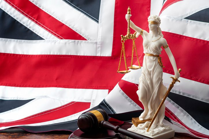 A stock photo of the statue of Themis goddess with a British flag on the background. 