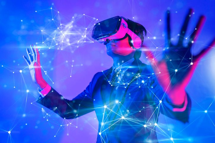 A stock image of a man wearing VR goggles in the neon lights. 
