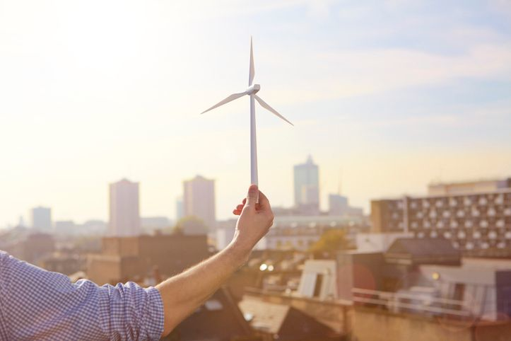 A stock photo featuring a man holding a wind turbine model
