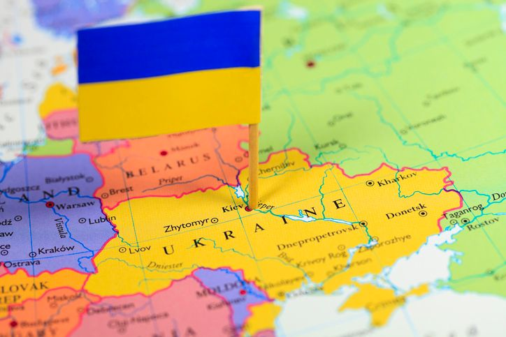 A stock photo featuring a close-up map of Ukraine with a small Ukrainian flag on it
