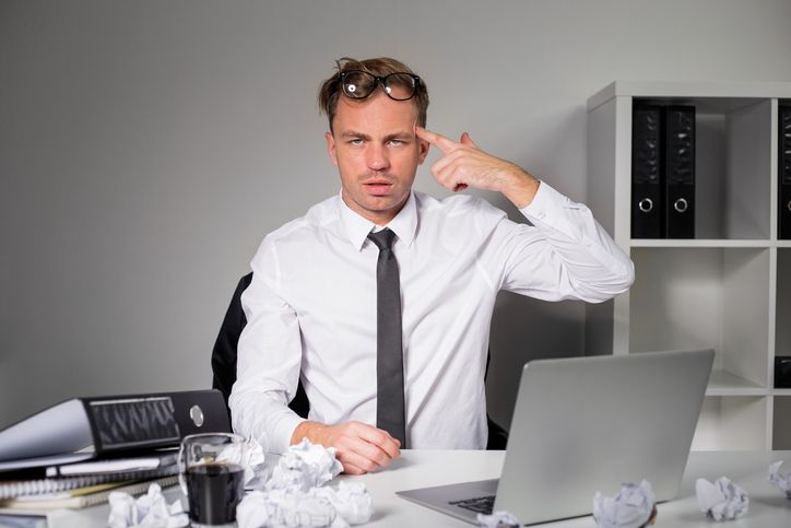 A stock photo featuring tired man at the office with a laptop on his table. 