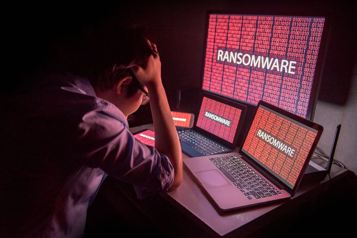 A stock photo of a desperate man in front of the monitors that read "ransomware."
