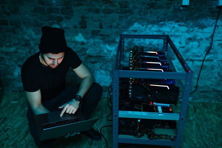 A stock photo of a data centre technician with laptop near the mining rig.