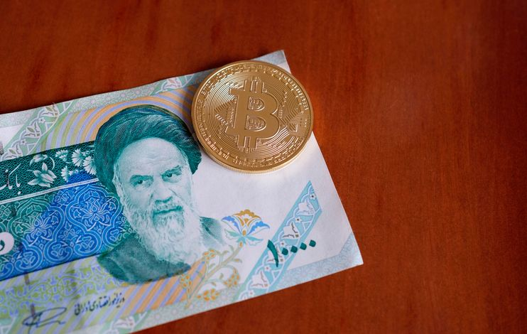 An image of Bitcoin coin on Iranian Rial banknote. 