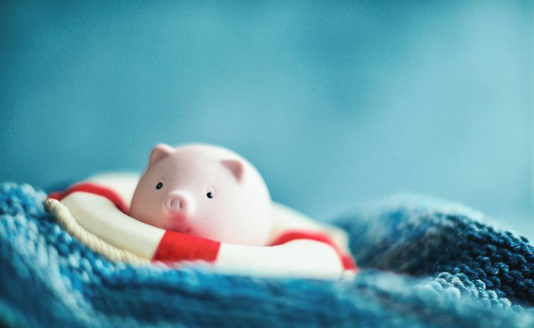 A stock photo of a piggy bank wearing a lifebelt on waves.