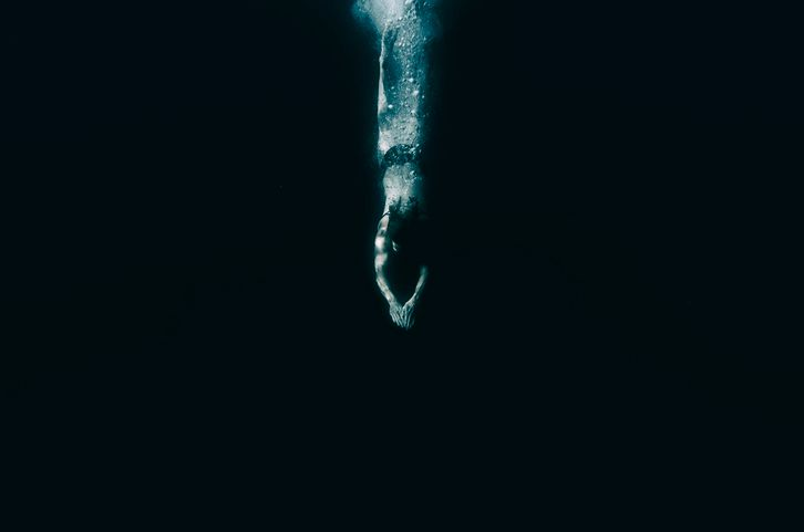 A stock photo of a woman diving in the dark water. 