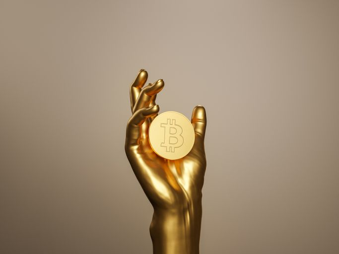 A stock photo of a golden hand holding Bitcoin. 