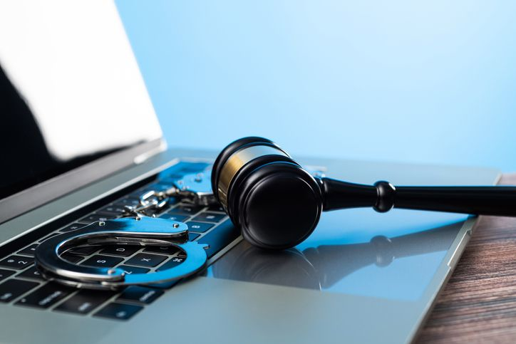 Gavel and handcuffs on laptop keyboard - stock photo
