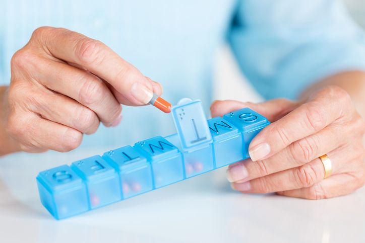 A stock photo featuring senior woman holding daily pill container.