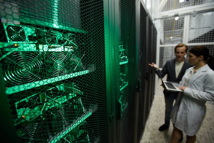 A stock image of two data center technicians near the ASIC mining rig. 