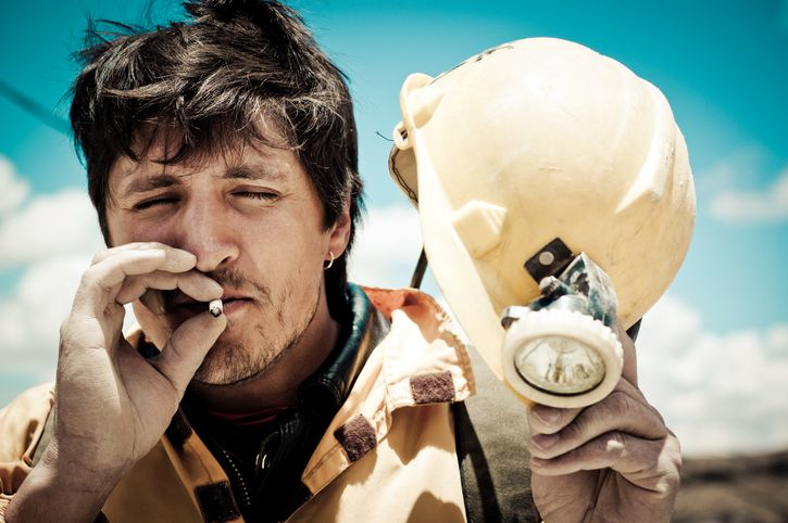 Tired miner smoking after work. 