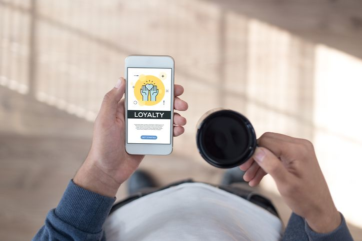 A stock photo featuring man holding a smartphone with the customer loyalty program. 