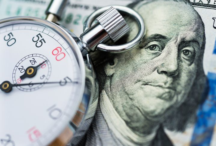 A stock photo of a dollar banknote and a stop watch. 