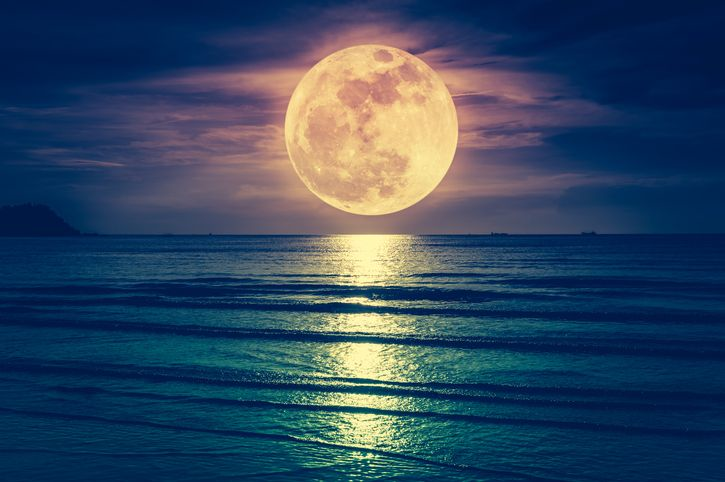 Big yellowish Moon hanging above a calm seashore