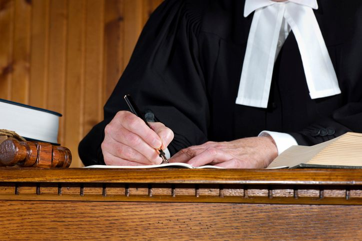 Judge in a robe taking notes - stock photo