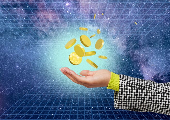 A collection of gold coins hove above a human hand in a virtual space