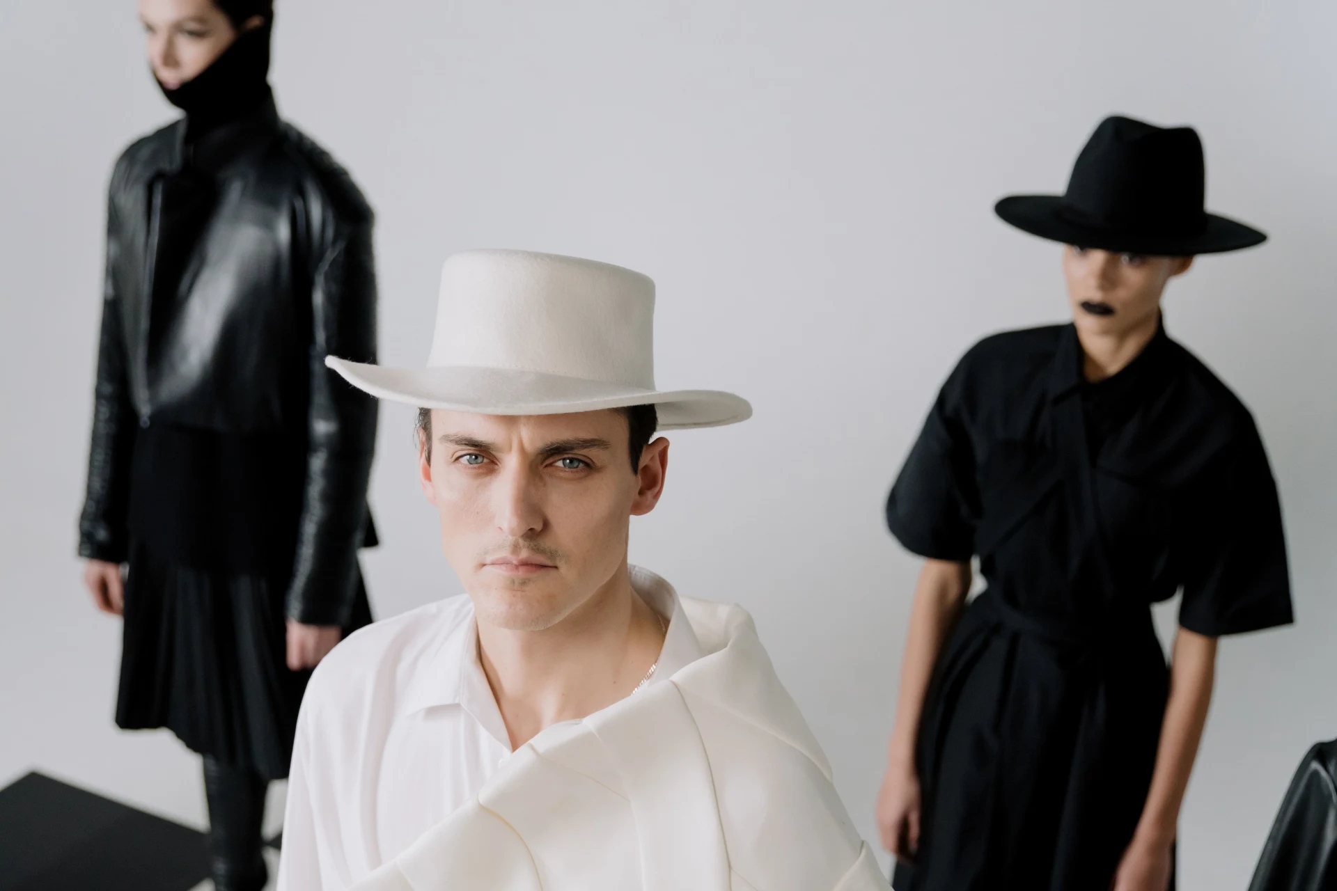 A man wearing a white hat and two women wearing black hats