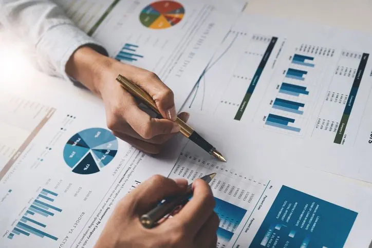 A stock photo of two hand writing over the financial report.