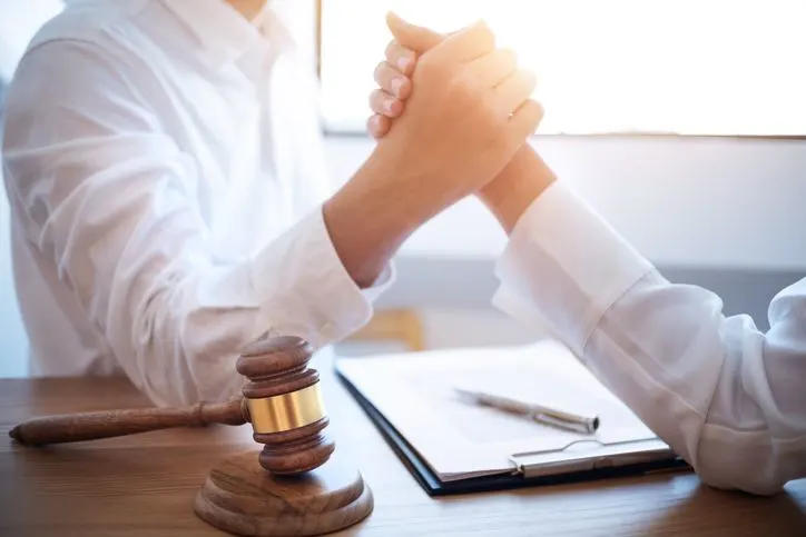 A stock photo featuring two businessman arm wrestling with a lawyer hammer in workplace.