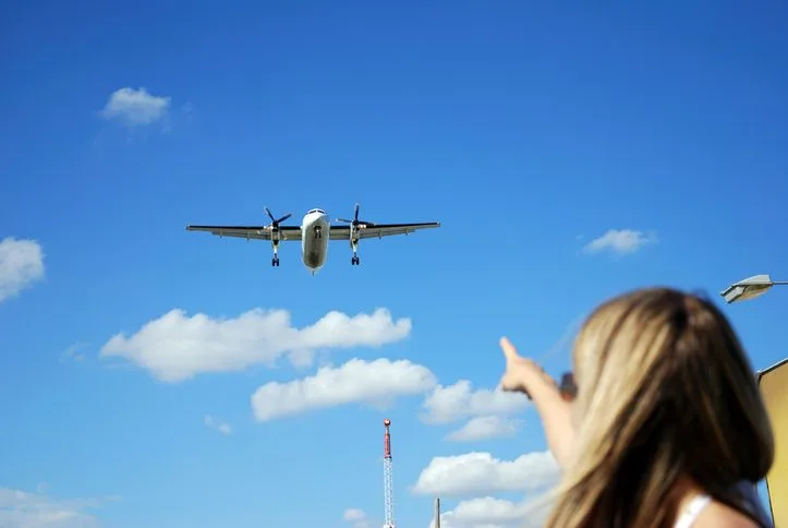 Stock foto of a girl pointing at the landing plane.