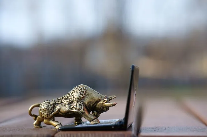 A stock photo featuring a metal bull with a laptop