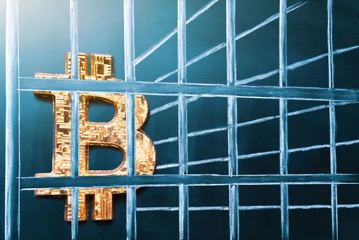 A stock image of a Bitcoin logo behind bars. 