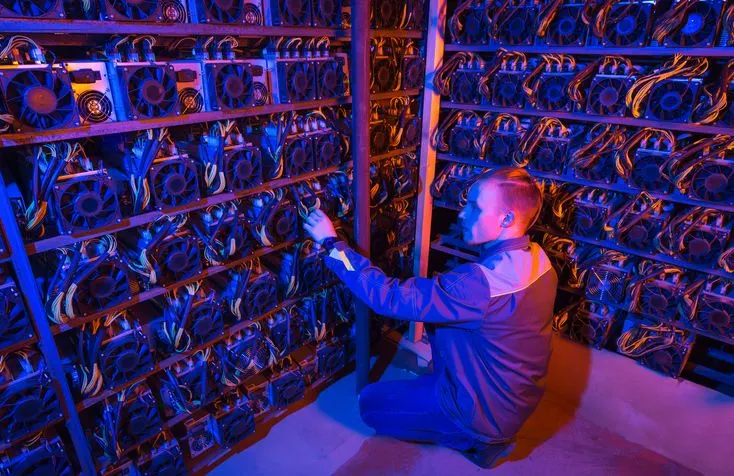 A stock photo featuring mining devices and data center technician in neon light. 