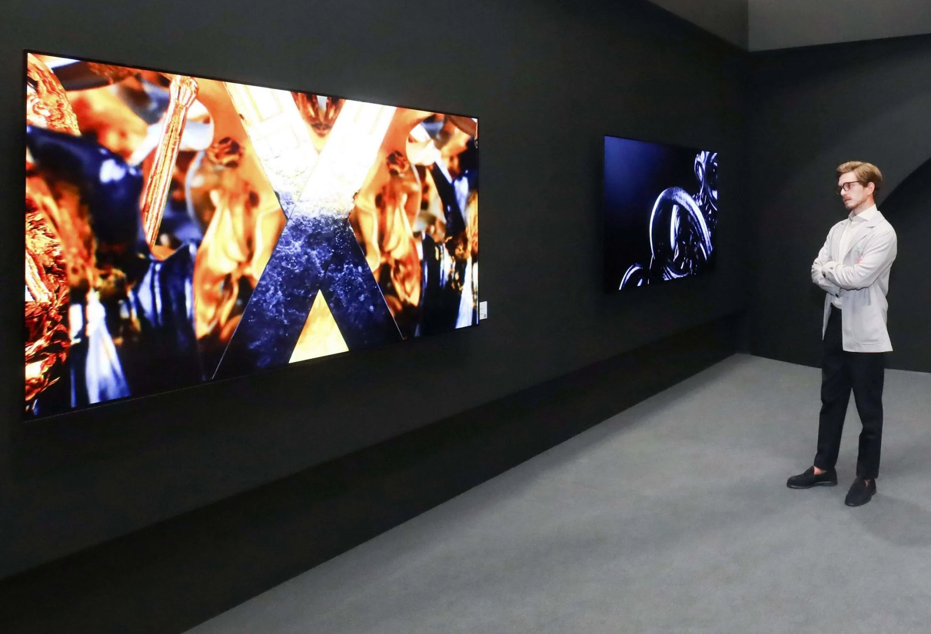 A photo of a young man looking at LG TV showcasing digital art. 