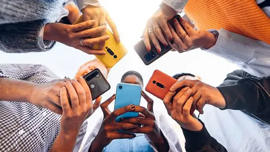 Teens in circle holding smart mobile phones
