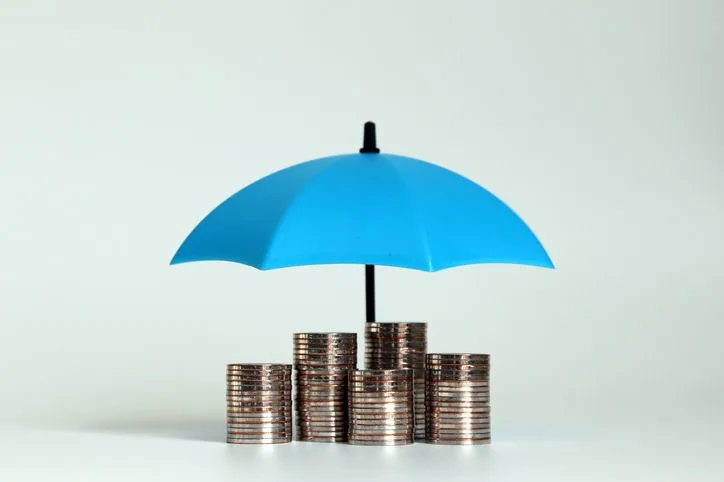 A stock photo featuring piles of coins under the blue umbrella.