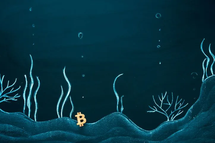 A stock image of the bitcoin symbol at the bottom of the sea.