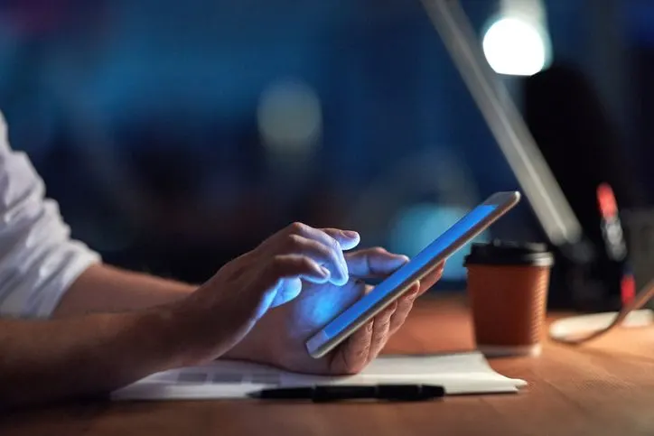 A stock photo featuring a businessman using smartphone late at night. 