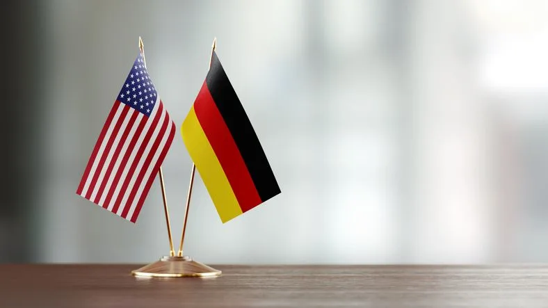 American and German flags standing side by side on a wooden counter