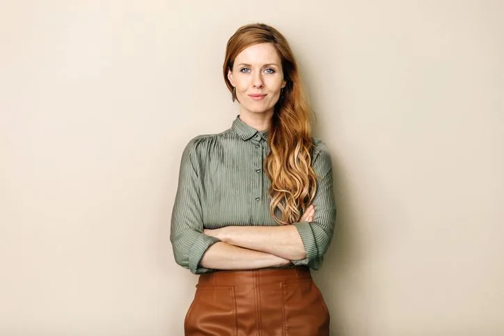 Businesswoman standing defiantly with arms folded, smiling