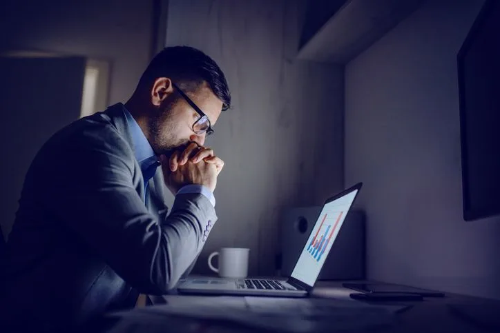 Man studying charts on his laptop late at night