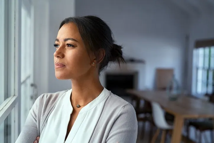 Thoughtful Black woman looking out her window