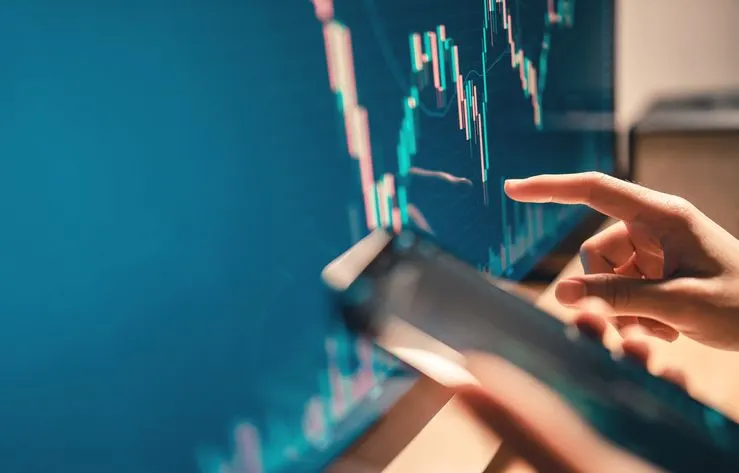 A close-up of a female hand checking on the candle chart. 