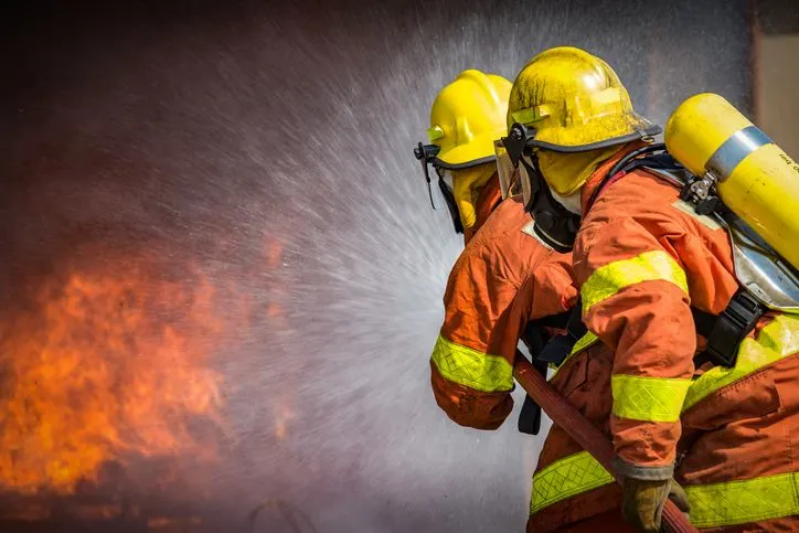 A stock photo of two firefighters spraying water on fire. 