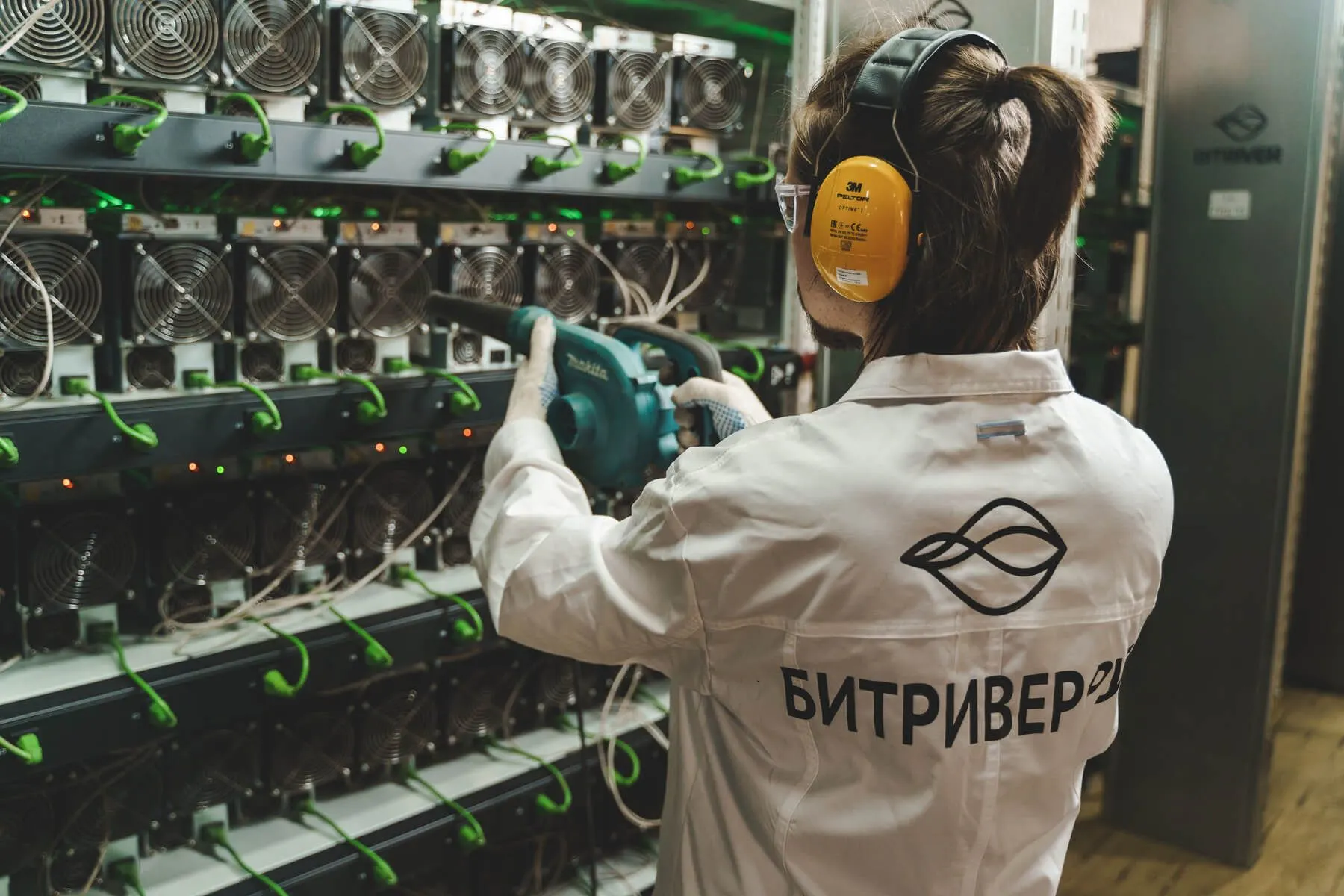 BitRiver employee cleaning mining devices with compressed air.