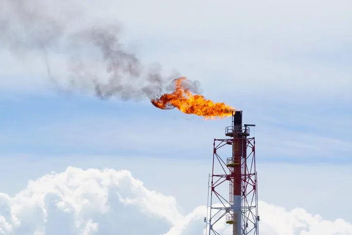 A stock photo of a flare stack against the blue cloudy sky. 
