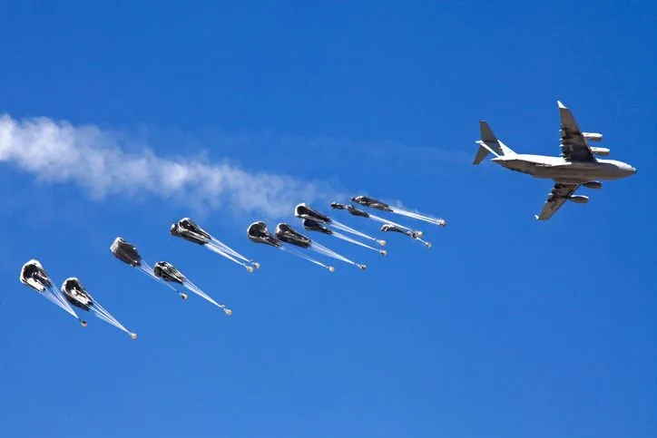 A stock photo of a military plane airdropping cargo. 