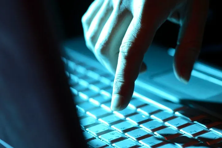 A stock photo of a finger touching keyboard in neon light. 