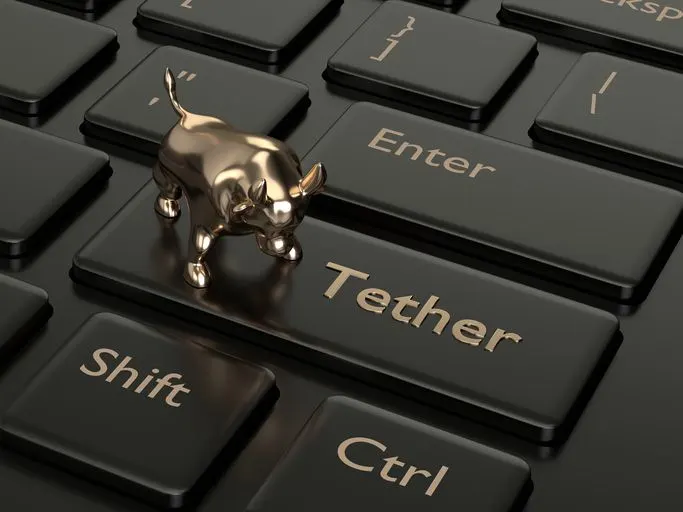 Bull figurine on a Tether button on a black and gold keyboard