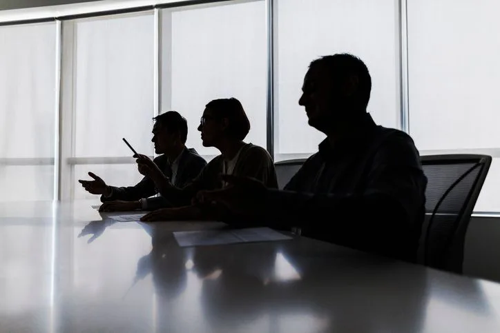 A stock photo of silhouettes of business people negotiating at the meeting table. 
